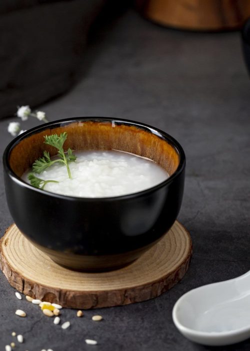 rice-soup-black-bowl-wooden-support-white-spoon